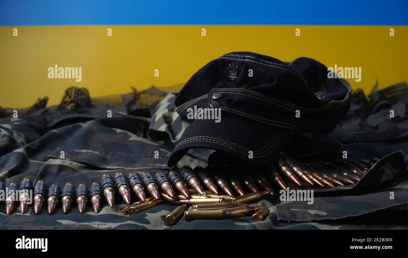 Blau-gelbe Flagge des ukrainischen Nationalsymbols, 5,56mm-Munition, Maschinengewehrkugeln Gürtel, Gewehrmunition in Zeitschriften, ukrainische Uniform und schwarze Militärmütze Stockfoto