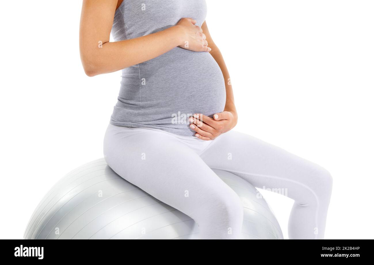 Ich kann es kaum erwarten, Euch zu treffen. Zugeschnittenes Bild einer Schwangeren, die ihren Bauch hält, während sie auf einem Übungsball sitzt. Stockfoto