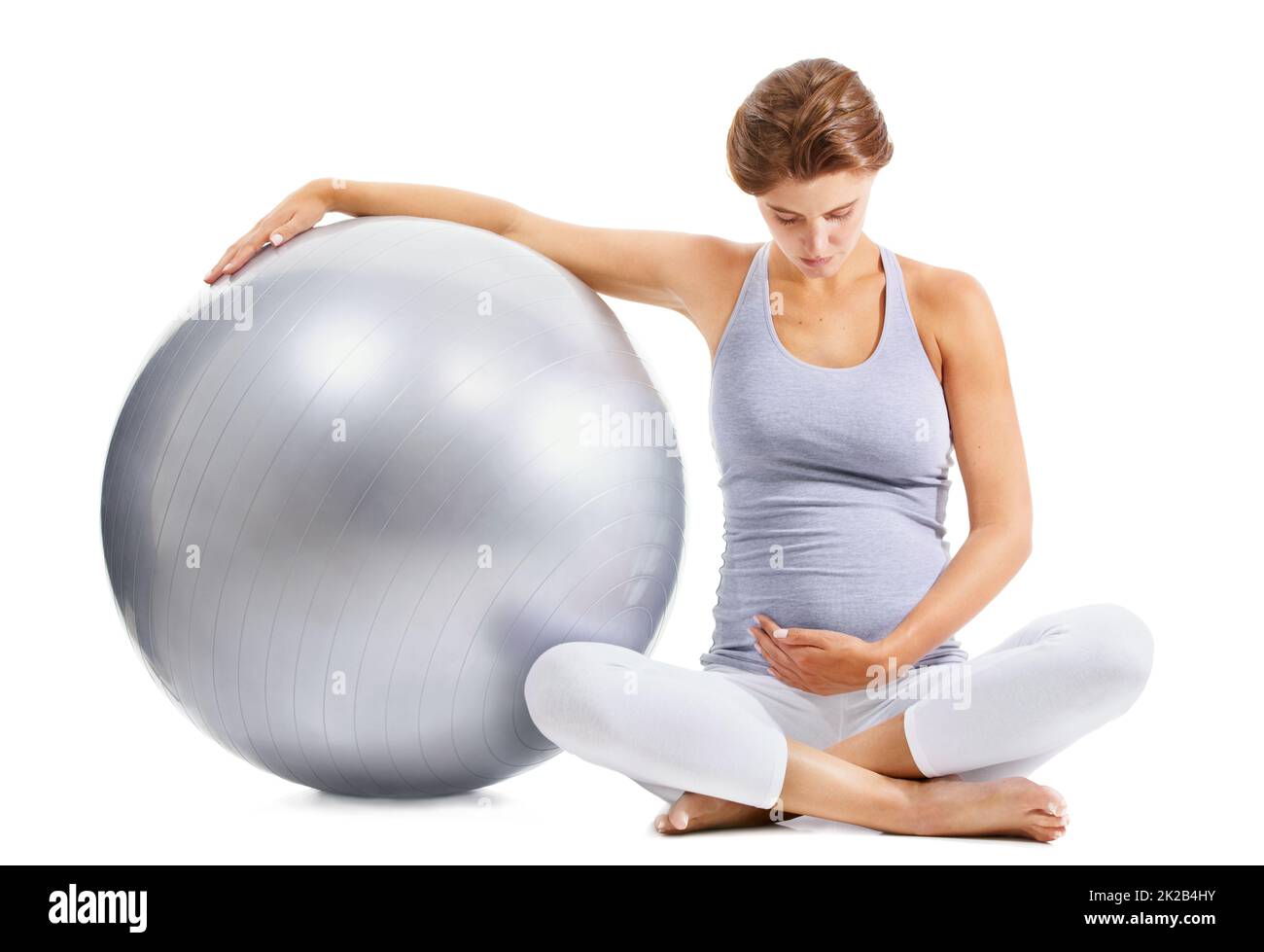 Kümmert sich um ihr Baby vor seiner Geburt. Eine fick-Schwangere blickt auf ihren Bauch, während sie einen Übungsball hält. Stockfoto