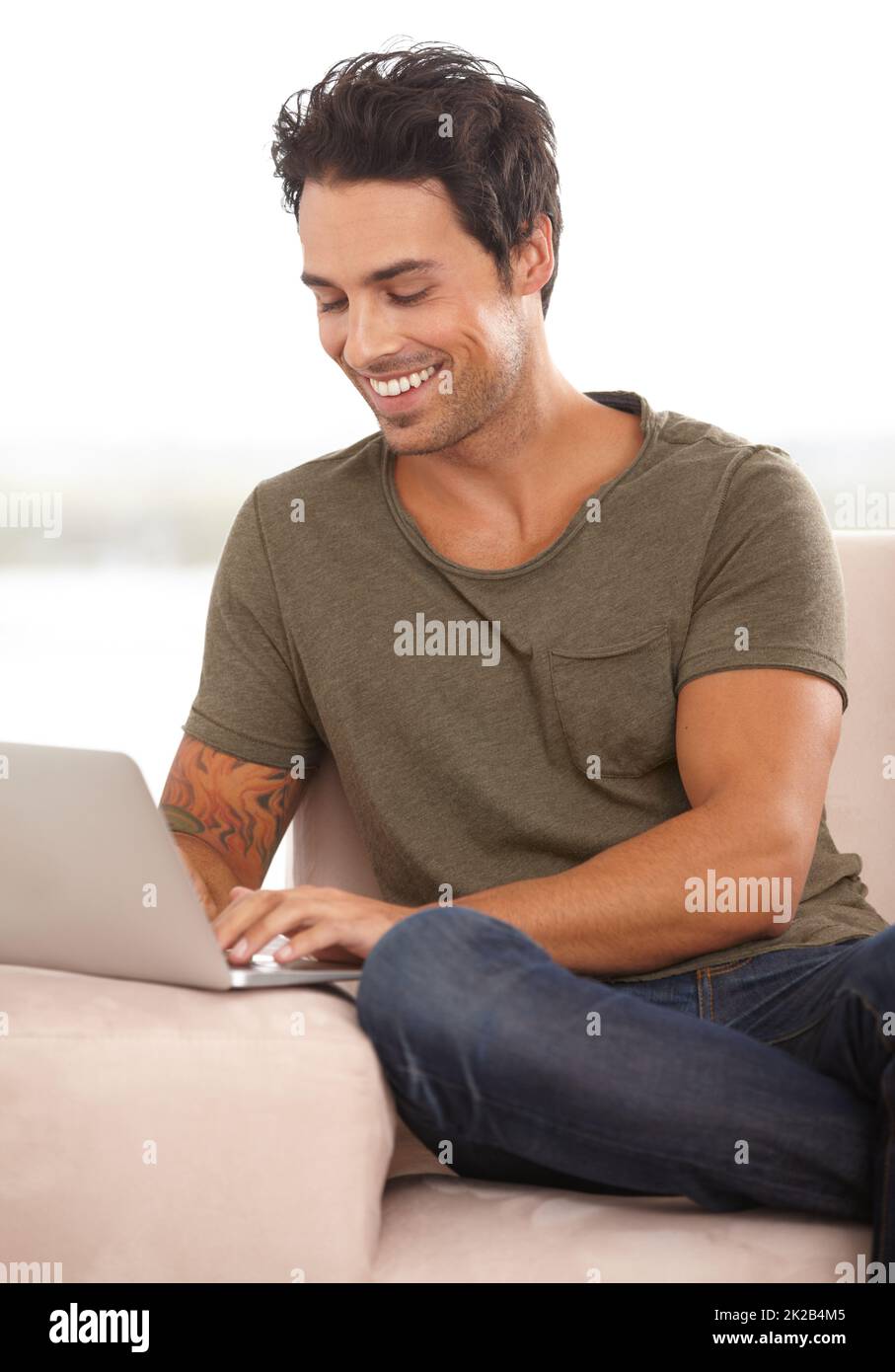 Eine freundliche E-Mail Ein hübscher junger Mann, der zu Hause an seinem Laptop arbeitet. Stockfoto
