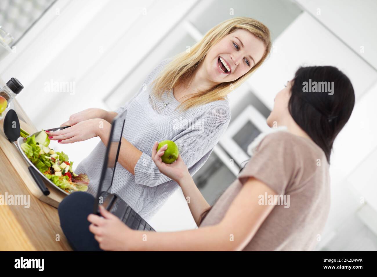 Sich dank ihrer Ernährung gesund fühlen. Zwei junge Frau, die in der Küche zu Hause einen Salat zubereitet. Stockfoto