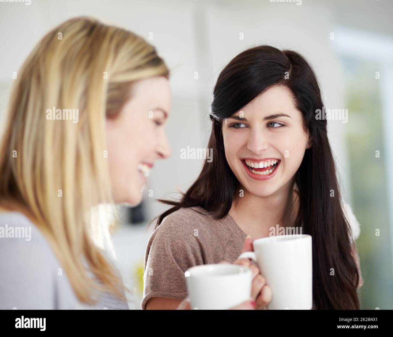 Nachholbedarf. Zwei glückliche junge Frauen, die zu Hause Kaffee trinken. Stockfoto