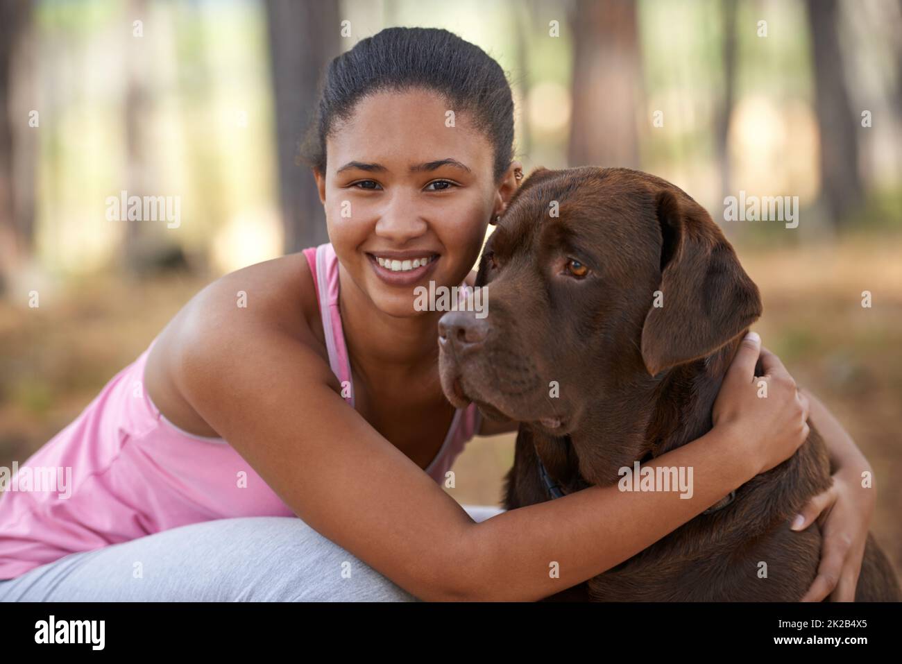 Ich verbringe Zeit mit meinem besten Freund. Eine junge ethnische Frau, die mit ihrem Hund draußen sackt. Stockfoto