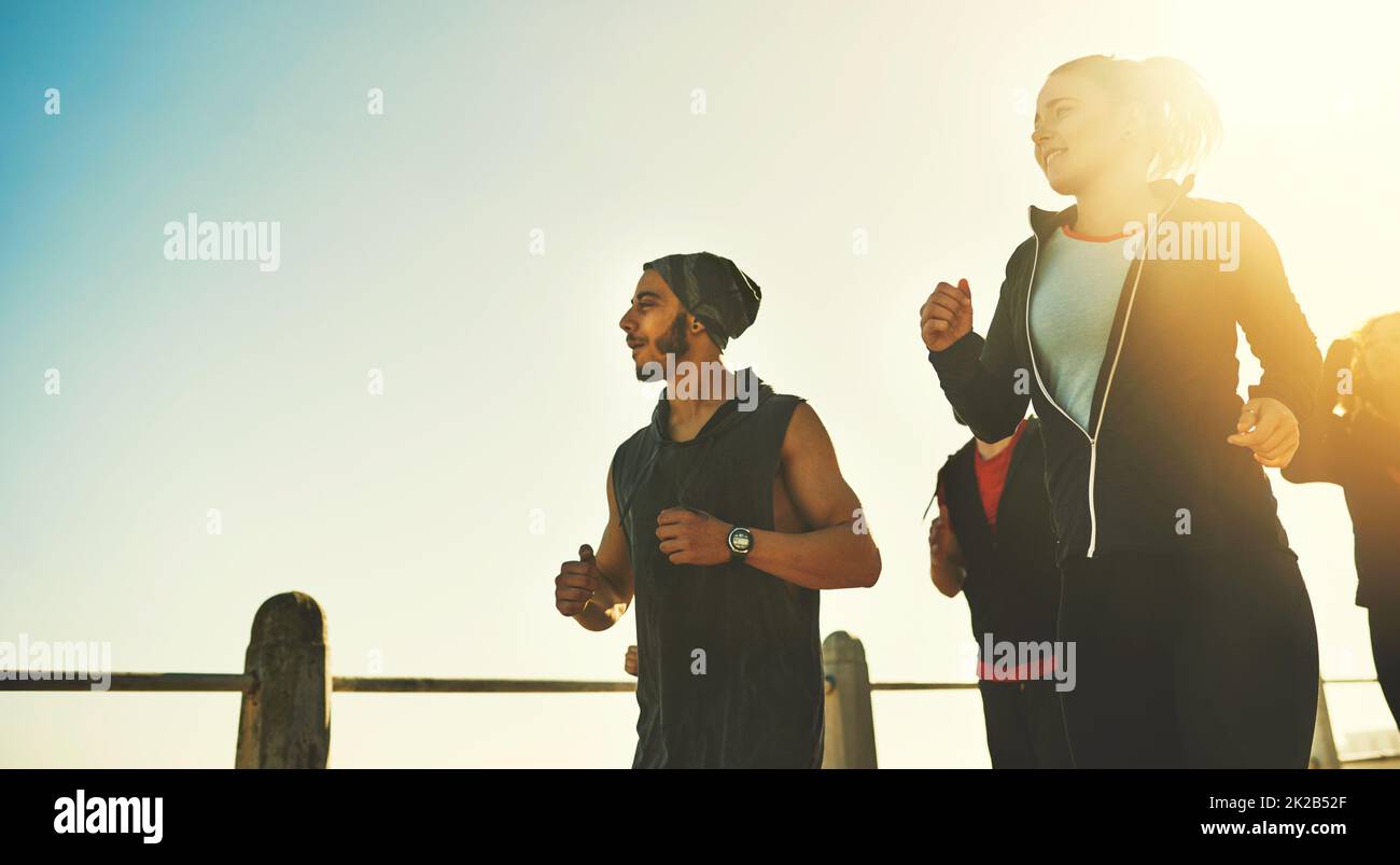 Sich mit Freunden fit machen. Aufnahme einer Fitnessgruppe, die auf der Promenade läuft. Stockfoto