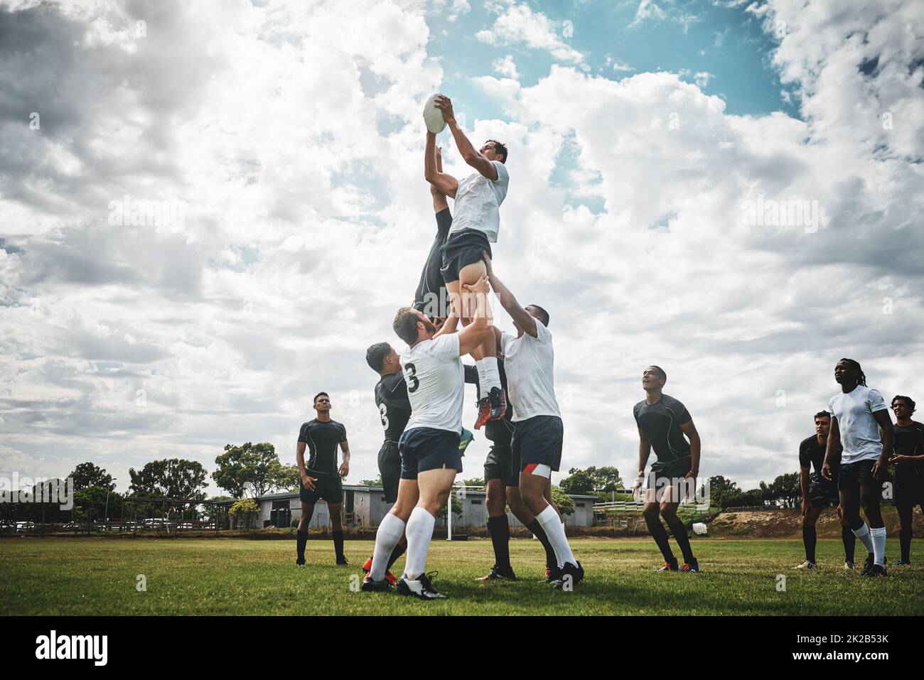 Greifen Sie nach dem Himmel. Aufnahme von zwei Rugby-Teams, die während einer Linie aus einem Rugby-Spiel draußen auf einem Filed um einen Ball kämpfen. Stockfoto