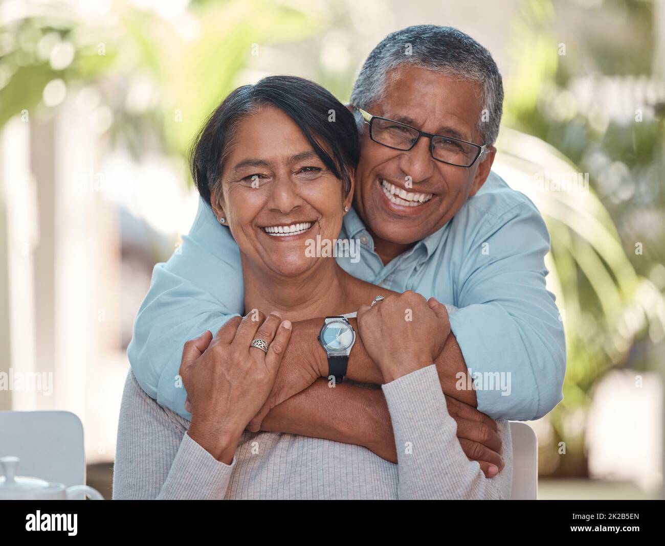 Portrait, ältere Menschen und Paare verbinden sich zu Hause auf einer Terrasse, umarmen, lachen und entspannen sich gemeinsam im Freien. Liebe, Ruhestand und glückliche Senioren genießen ihre Stockfoto