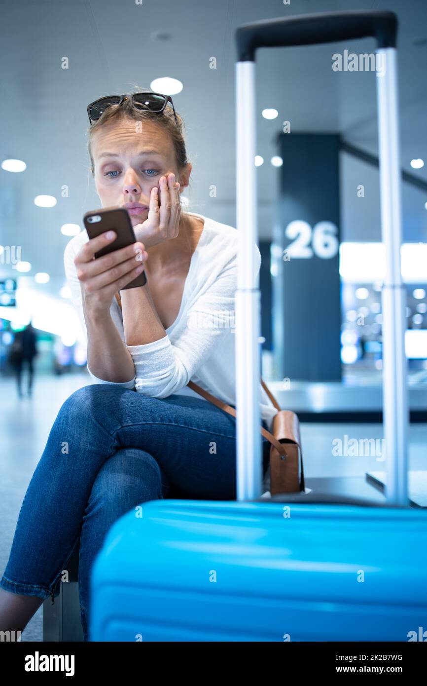 Junge Frau mit ihrem Gepäck an einem internationalen Flughafen, bevor es durch den Check-in die Sicherheit prüfen Sie vor Ihrem Flug und Stockfoto