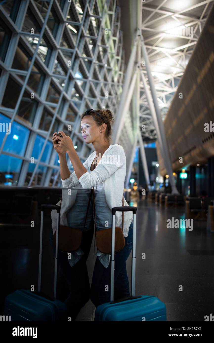Junge Frau mit ihrem Gepäck an einem internationalen Flughafen und warten auf Ihren Flug in der Lounge Zone, nachdem man durch die Sicherheitskontrolle Verfahren Stockfoto