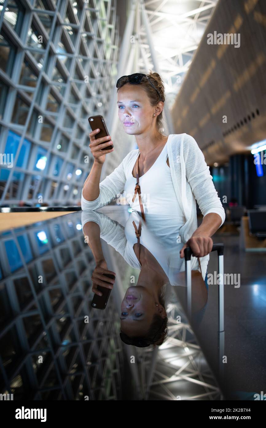 Junge Frau mit ihrem Gepäck an einem internationalen Flughafen und warten auf Ihren Flug in der Lounge Zone, nachdem man durch die Sicherheitskontrolle Verfahren Stockfoto