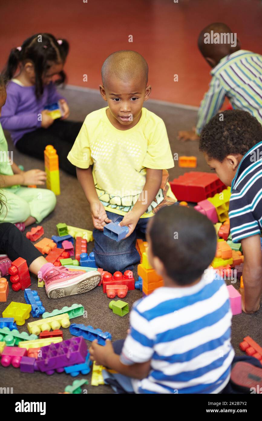 Teilen ist fürsorglich. Spielzeit für eine Gruppe von kleinen Kindern, die mit Plastikblöcken spielen. Stockfoto