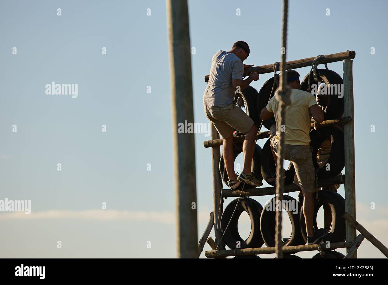 Trainieren Sie, wie es keine Ziellinie gibt. Aufnahme von Männern, die im Bootcamp über ein Hindernis klettern. Stockfoto