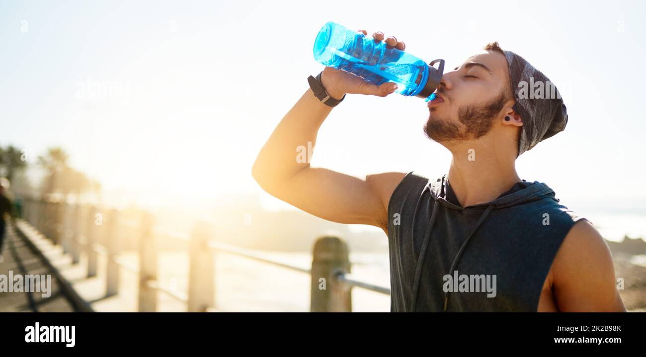 Wasser ist der wichtigste Nährstoff für aktive Menschen. Aufnahme eines sportlichen jungen Mannes, der beim Training im Freien Wasser trinkt. Stockfoto