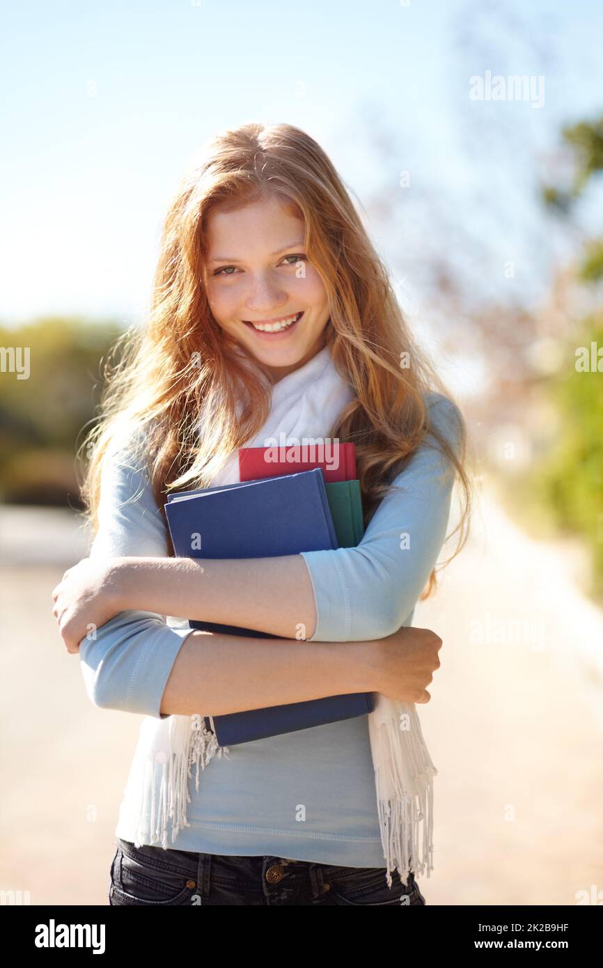 Sie liebt ihre Bücher. Porträt eines jungen Mädchens, das ihre Schulbücher nahe an ihre Brust hält. Stockfoto