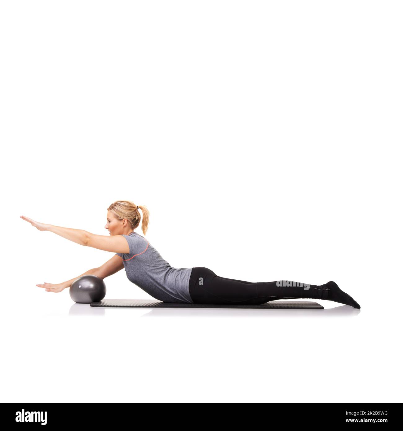 Ihr Workout bringt Ergebnisse. Eine junge Frau, die einen Übungsball im Liegen benutzt - isoliert. Stockfoto
