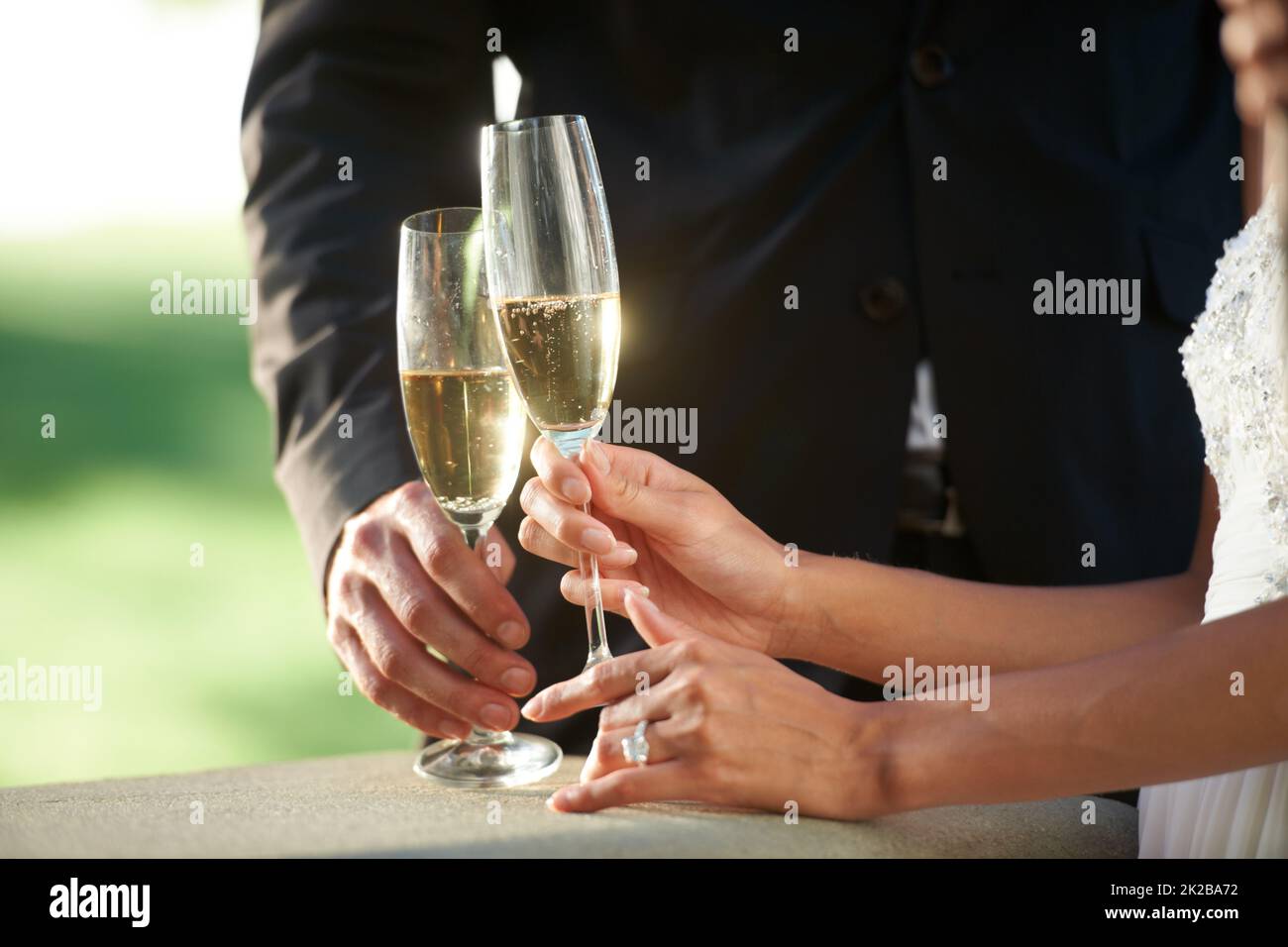 Bereit, ihre Liebe zu feiern. Beschnittene Ansicht einer jungen Braut und eines Bräutigams, die zusammen stehen und ihre Ehe toasten. Stockfoto