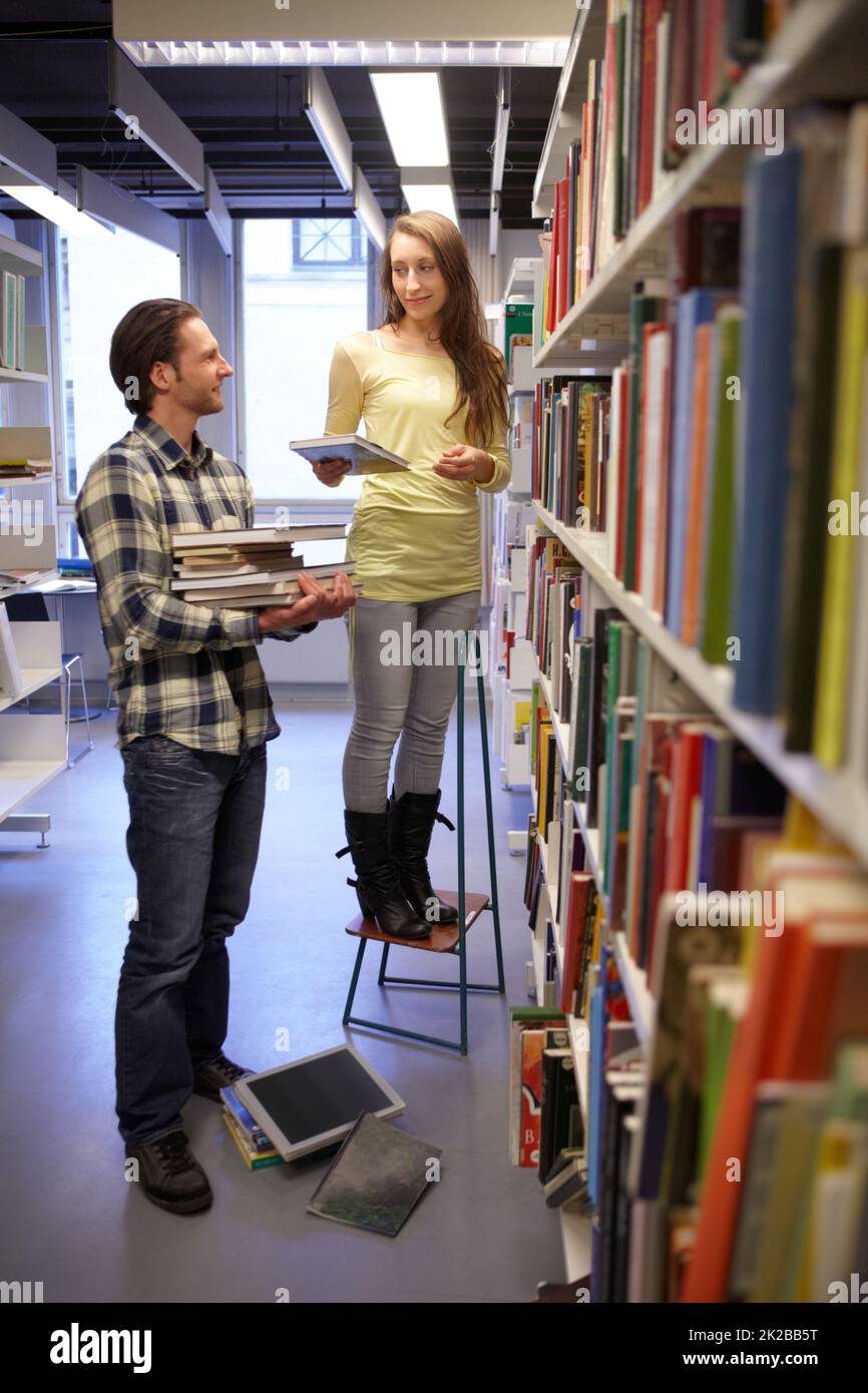 Ist dies das, was Sie gesucht haben. Aufnahme eines jungen Mannes und einer jungen Frau, die Bücher aus einem Bücherregal auswählen. Stockfoto