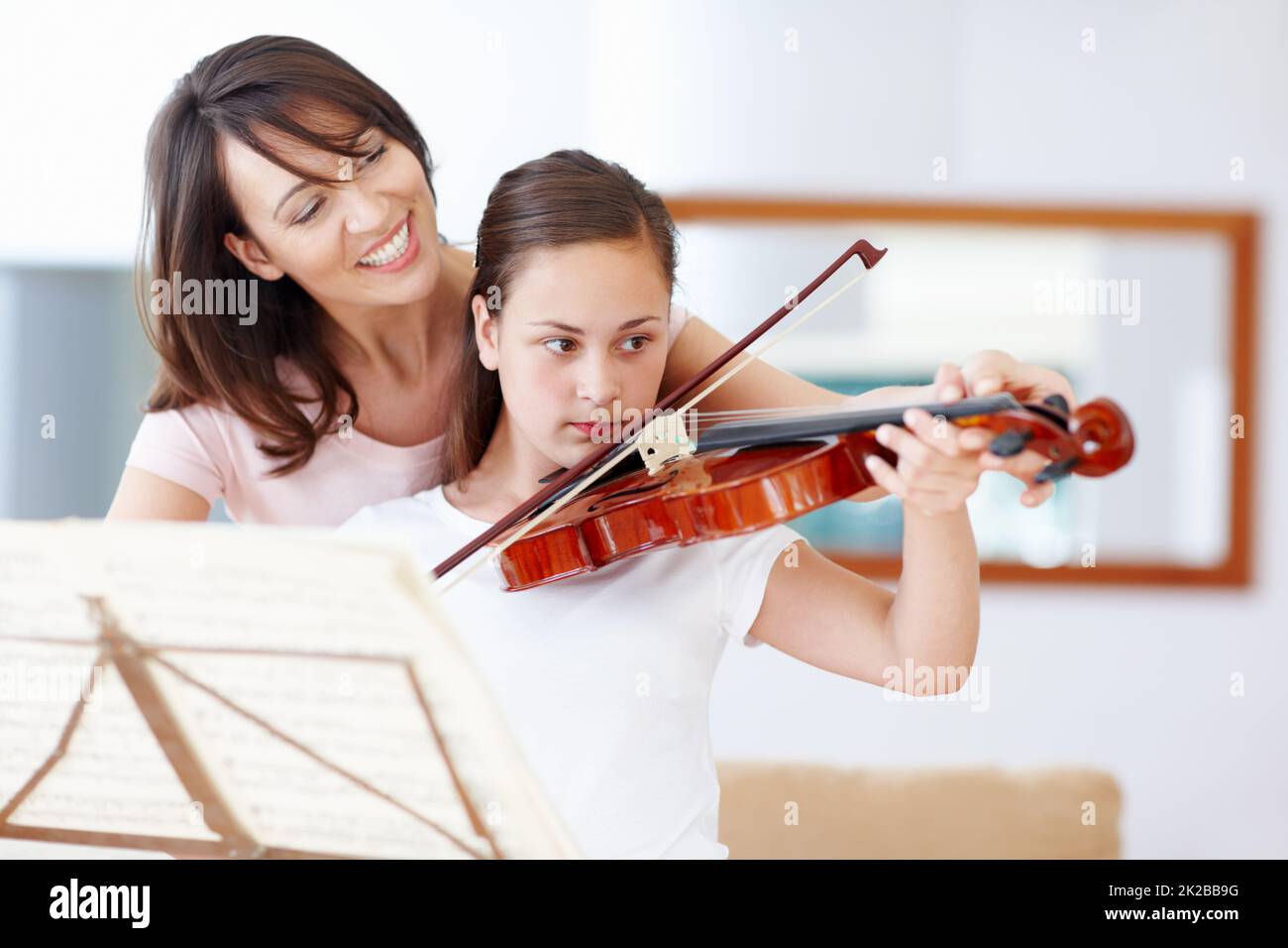 Übung macht den Meister, mein Mädchen. Eine Mutter hilft ihrer Tochter, während sie die Geige praktiziert - Copyspace. Stockfoto