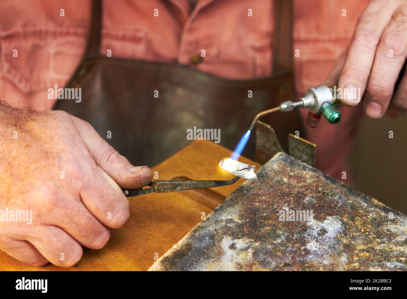 Anwendung von Wärme - Schmuckherstellung. Beschnittene Ansicht eines Juwelierherstellers bei der Arbeit mit einer kleinen Acetylenbrenner. Stockfoto