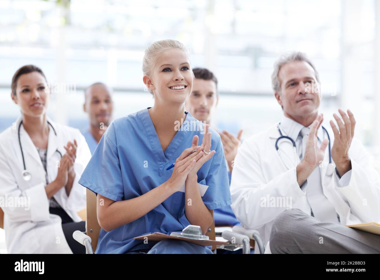 Wir feiern bahnbrechende Erfolge im Gesundheitswesen. Ärzte und Krankenschwestern applaudieren ihrem Dozenten. Stockfoto