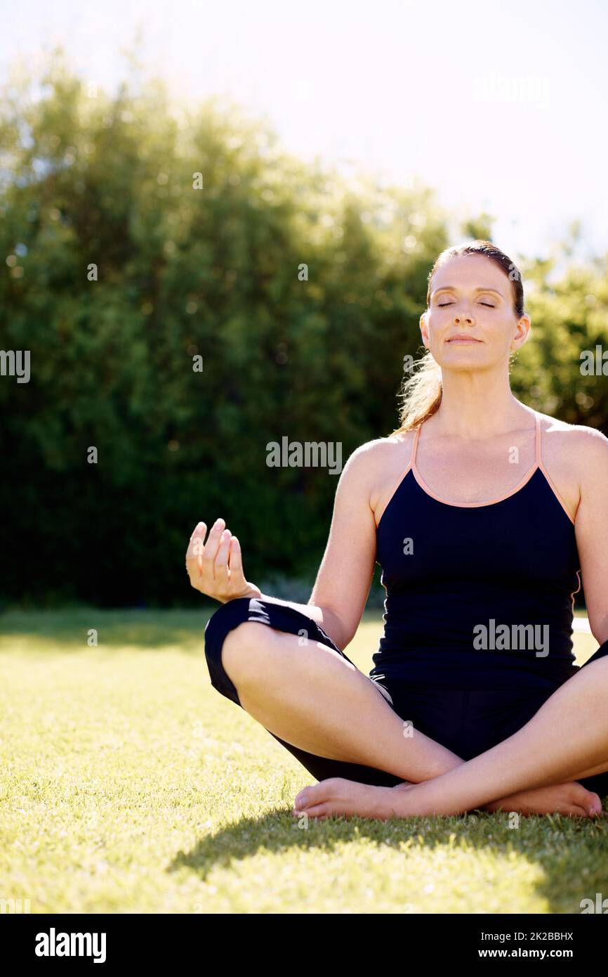 Achtsame Meditation. Eine attraktive Frau, die auf dem Gras sitzt und meditiert. Stockfoto