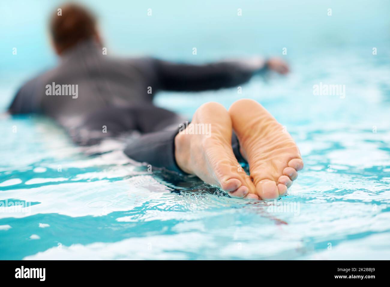 Eure Welle wartet auf euch. Rückansicht eines Mannes, der in klarem blauen Wasser surft. Stockfoto