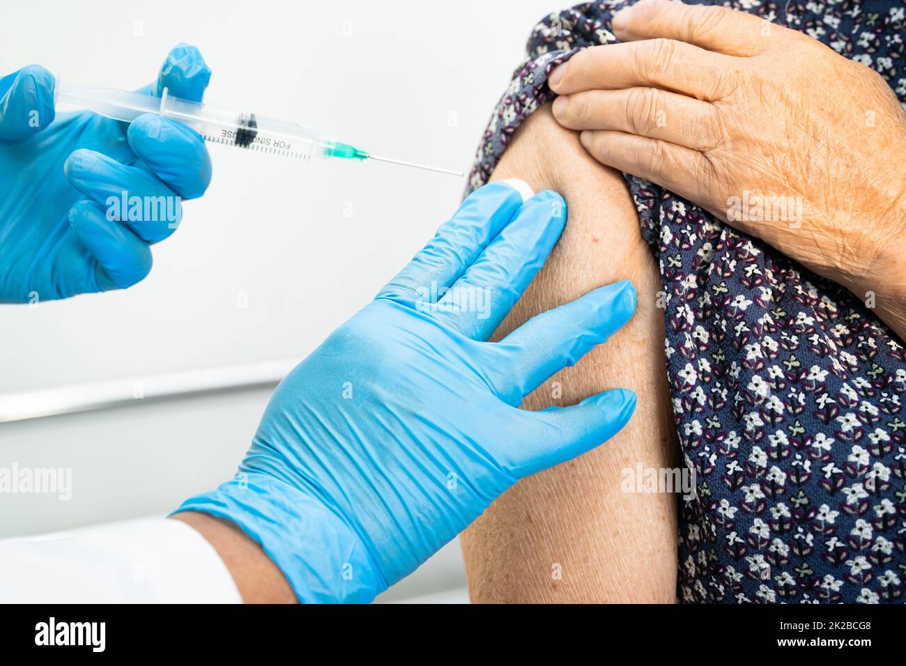 Ältere asiatische ältere Frau, die vom Arzt einen Covid-19- oder Coronavirus-Impfstoff erhält, wird mit einer Injektion geimpft. Stockfoto