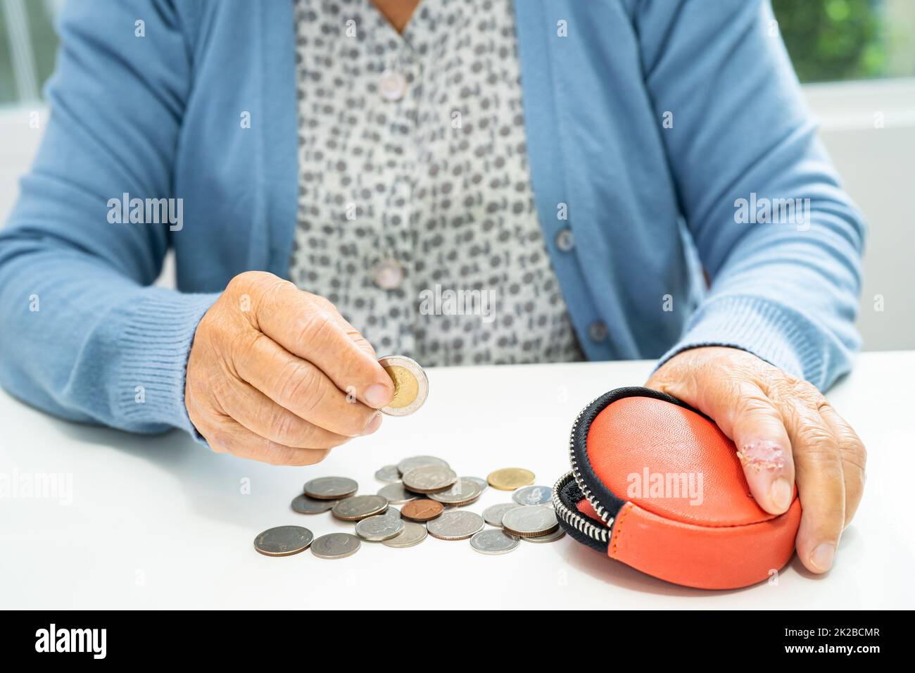 Asiatische ältere oder ältere alte Dame, die das Münzgeld im Geldbeutel zählt. Armut, Sparproblem im Ruhestand. Stockfoto