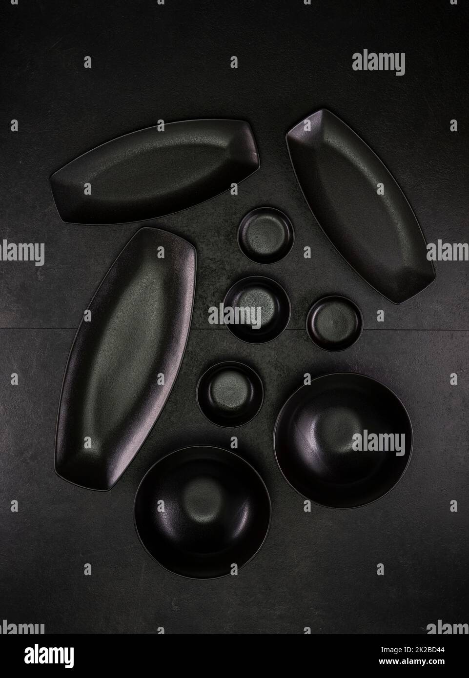 Schwarze Teller und Schüsseln auf schwarzem Hintergrund Stockfoto