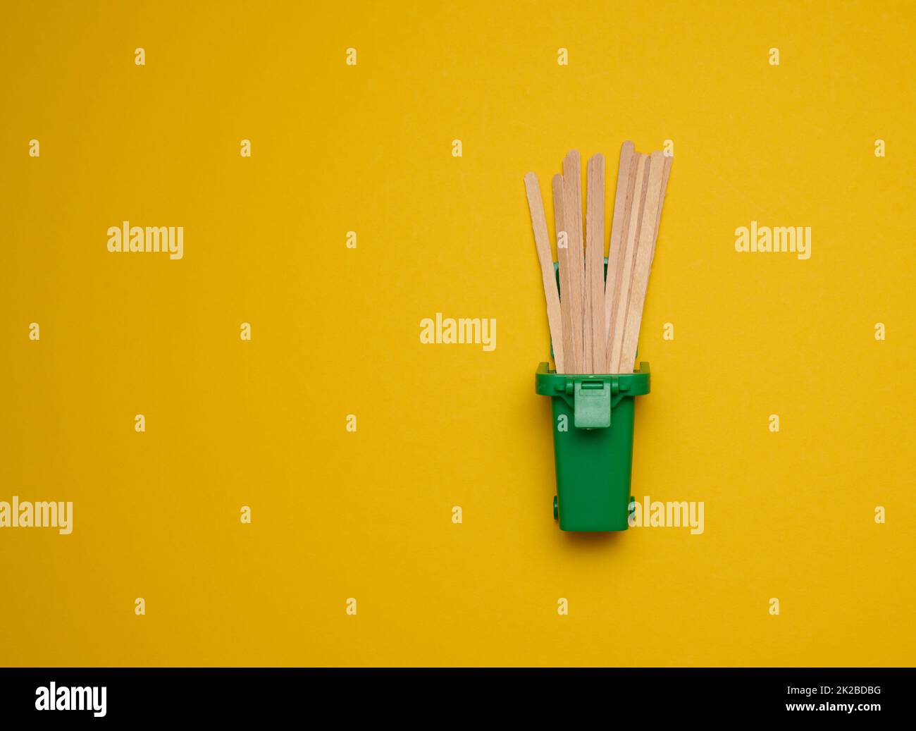 Einweg-Holzstäbchen zum Rühren von heißen Getränken auf gelbem Hintergrund. Kaffee- und Teelöffel Stockfoto