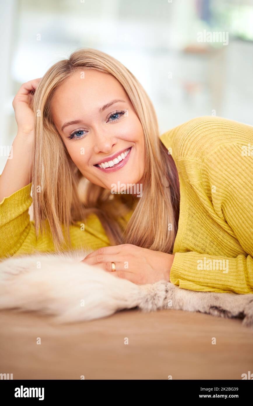Lust auf Gesellschaft...Porträt einer jungen Frau, die lächelt, während sie in ihrem Haus auf dem Boden liegt. Stockfoto