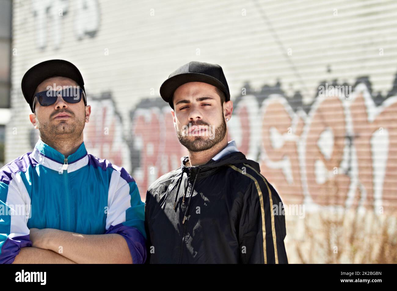 Das Leben auf der Straße. Zwei ernsthafte Männer stehen vor einer Graffiti-Wand. Stockfoto