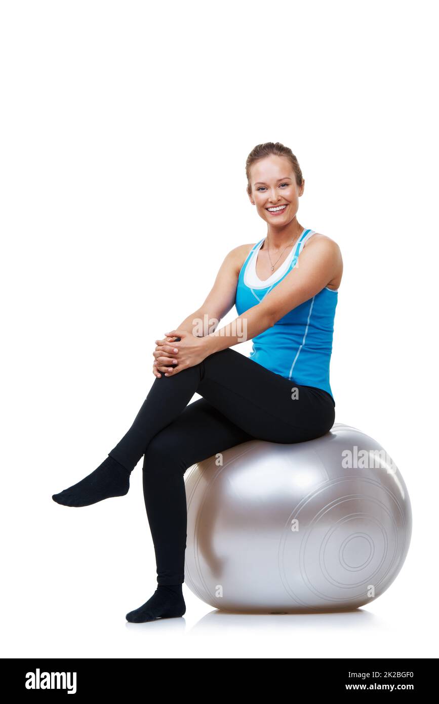 Ich fühle mich nach einer schweren Arbeit immer gut. Porträt einer lächelnden Frau, die auf ihrem Übungsball sitzt. Stockfoto