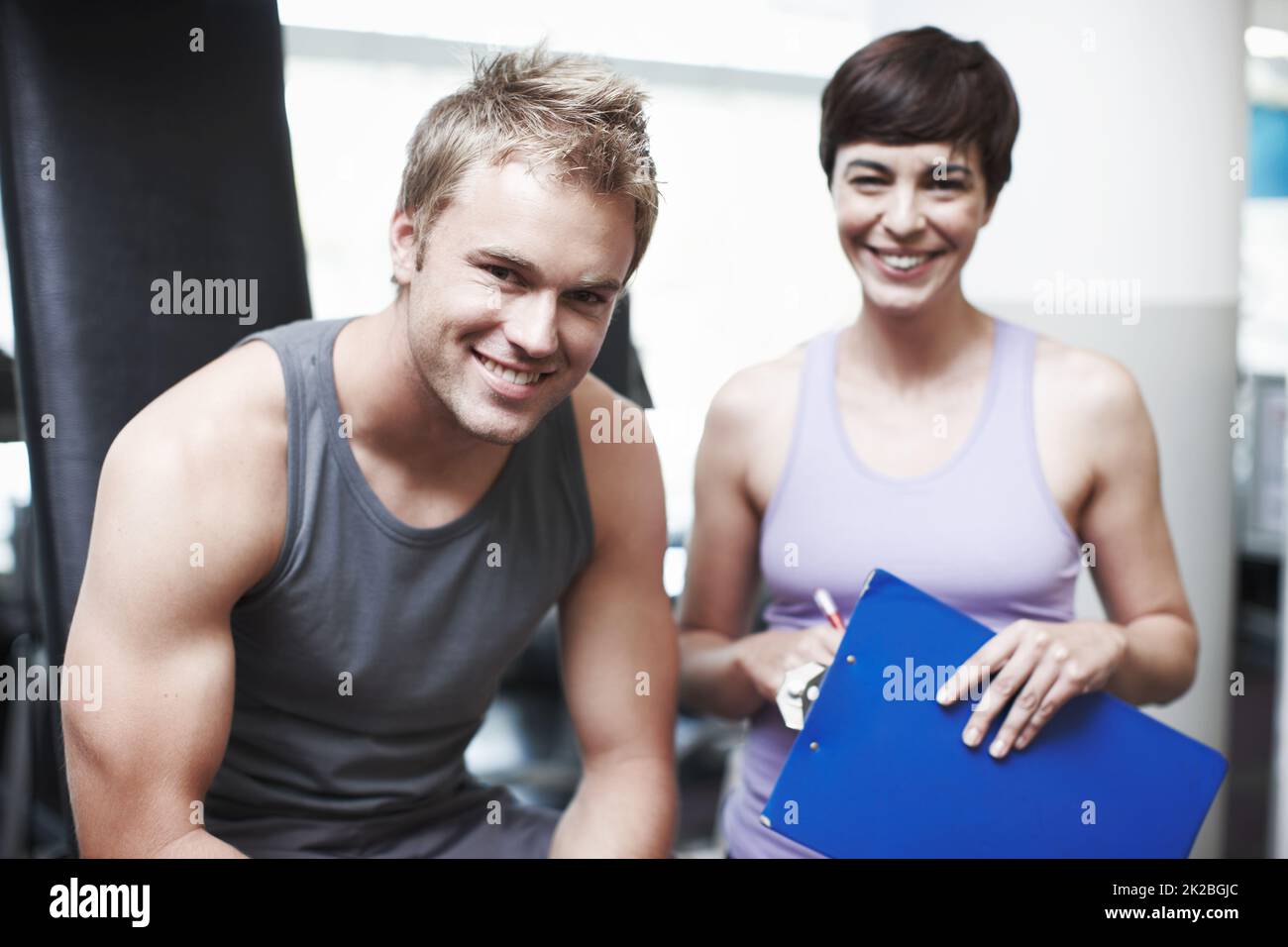 Sie hält mich motiviert. Beschnittenes Porträt eines hübschen jungen Mannes und seines persönlichen Trainers im Fitnessstudio. Stockfoto