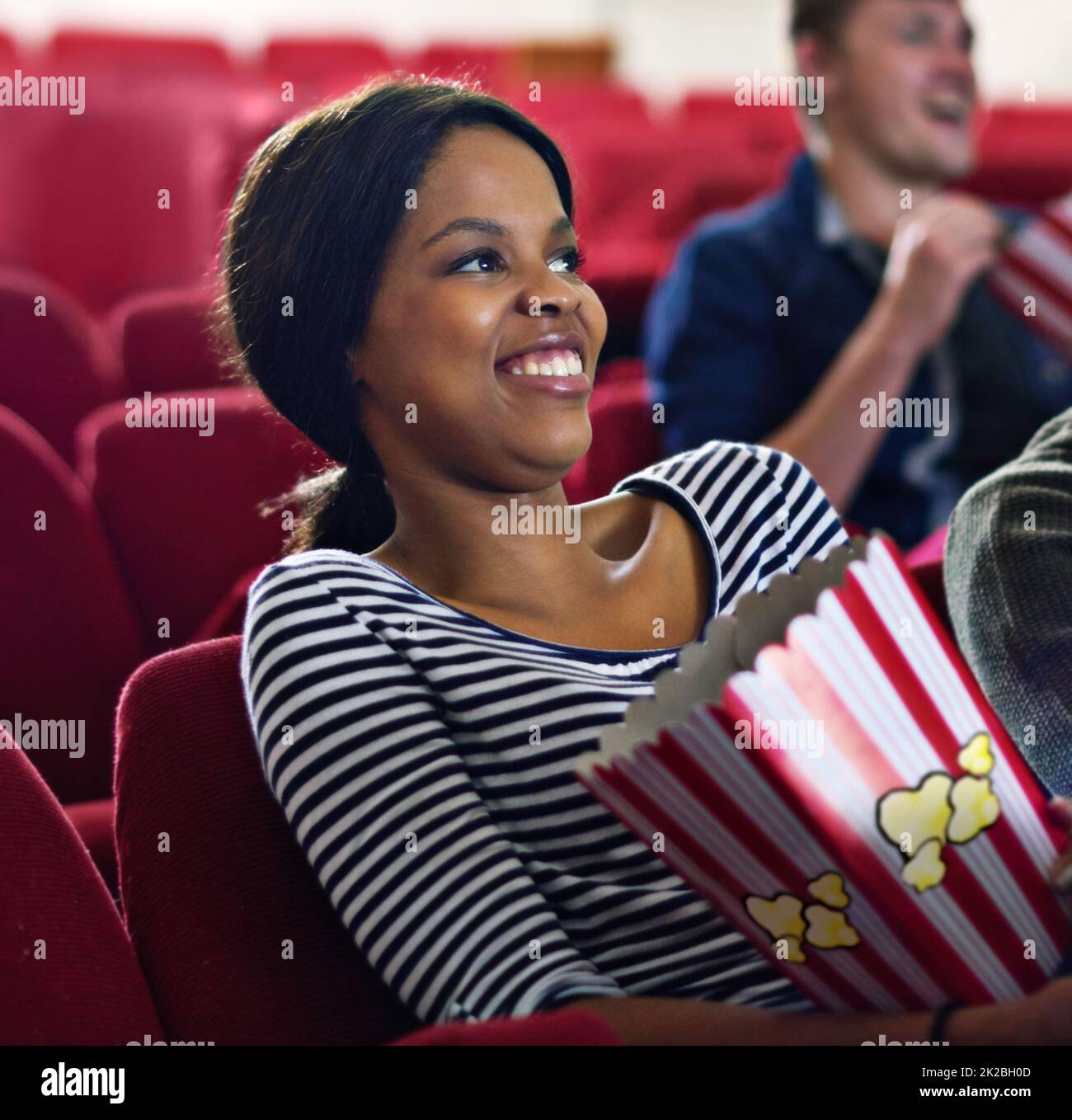 Nichts wie eine rom-com, um meine Stimmung aufzuhellen. Aufnahme einer lachenden Frau, während sie einen Film im Kino ansah. Stockfoto