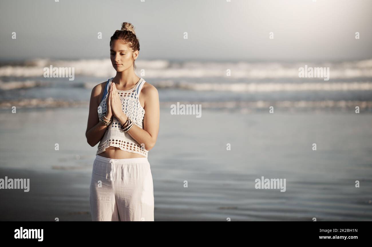 Überlegen Sie sich, wo Sie Ihre Yoga-Routine ruhiger machen können. Kurzer Screenshot einer attraktiven jungen Frau, die am Strand Yoga praktiziert. Stockfoto