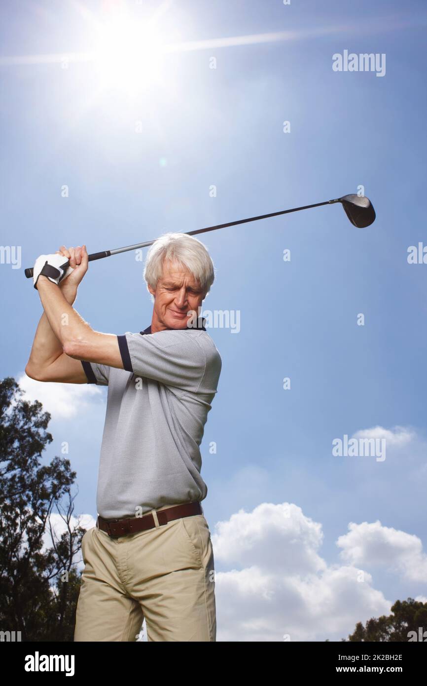 HES perfektionierte seinen Schwung über die Jahre. Senior Mann in vollem Gange während einer Runde Golf gegen einen blauen Himmel. Stockfoto