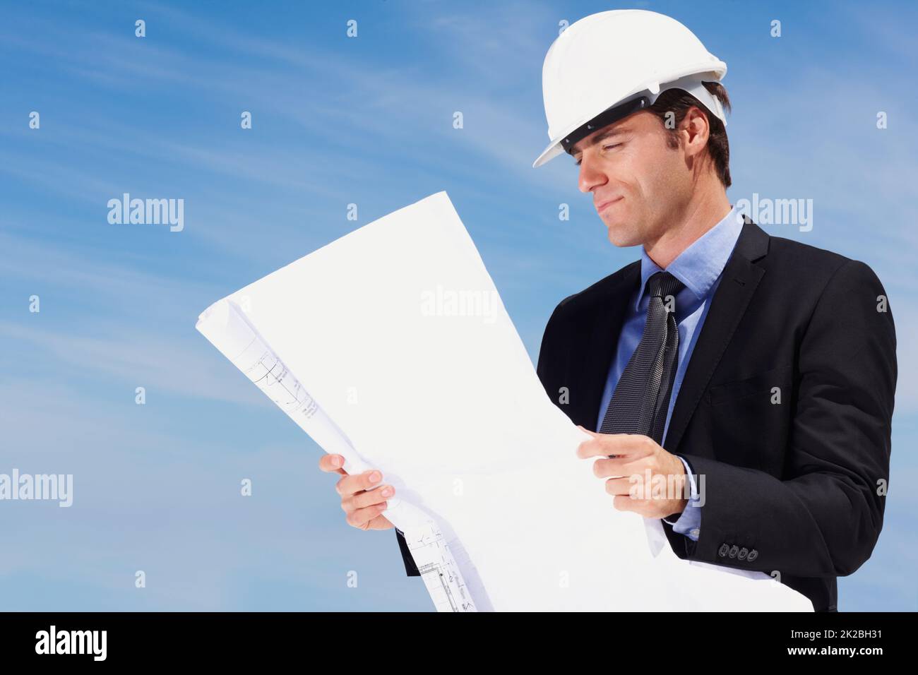 Intelligenter Architekt, der einen neuen Bauplan ansieht. Porträt eines intelligenten Architekten, der einen Bauplan betrachtet. Stockfoto