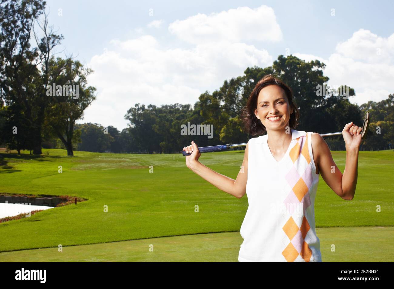 Golfs ihren Lieblingssport. Junge Frau, die auf dem Golfplatz steht und ihren Schläger über ihre Schultern hält. Stockfoto