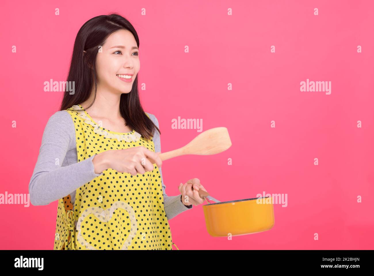 Glückliche junge Frau Hausfrau trägt Küchenschürze beim Kochen Stockfoto