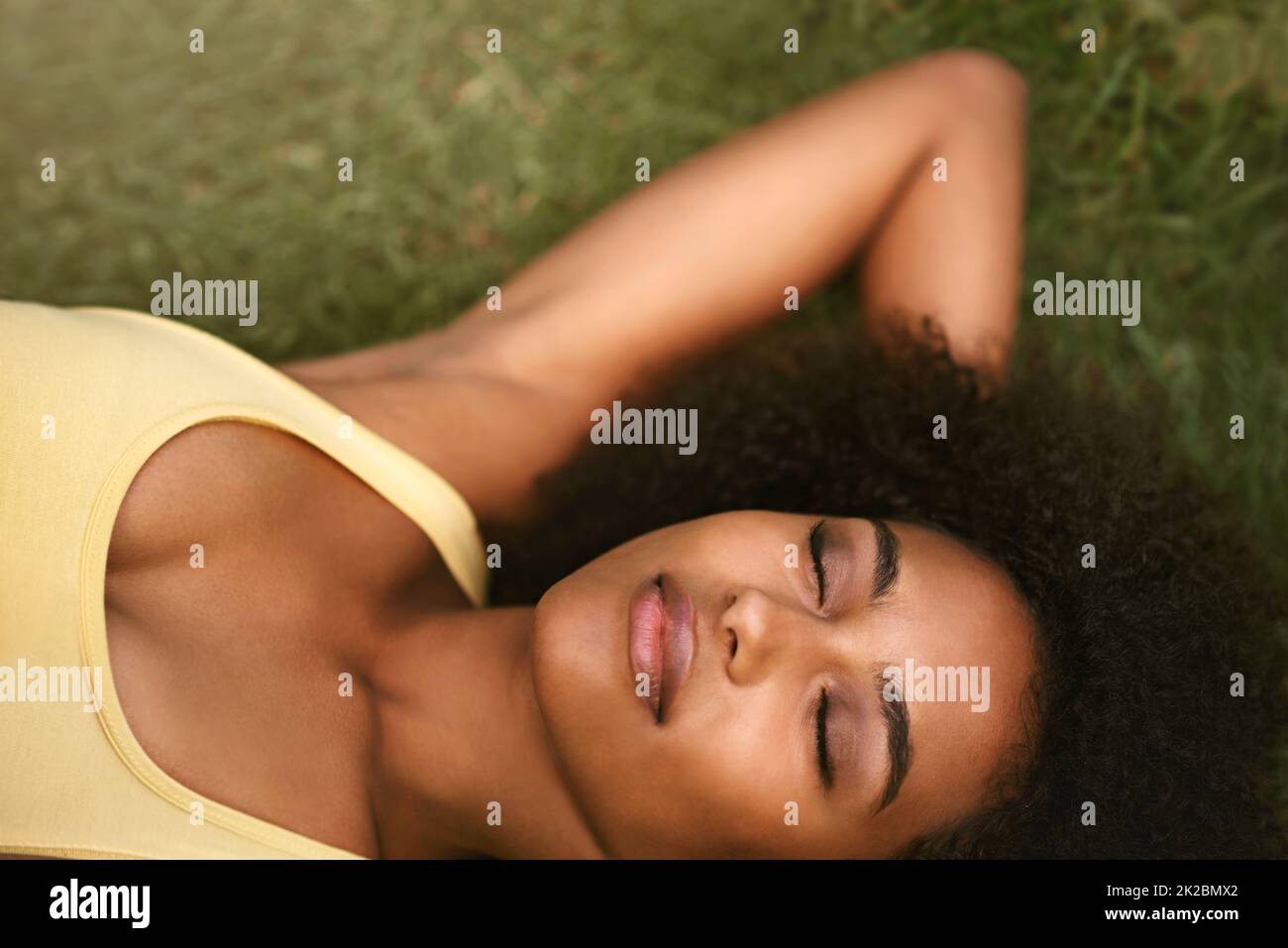 Absolute Glückseligkeit Aufnahme einer entspannten jungen Frau, die mit geschlossenen Augen auf dem Gras liegt. Stockfoto