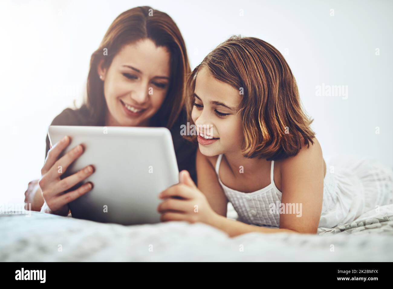 Wir haben Unterhaltung, um uns den ganzen Tag lang zu halten. Aufnahme eines kleinen Mädchens und ihrer Mutter mit einem digitalen Tablet. Stockfoto