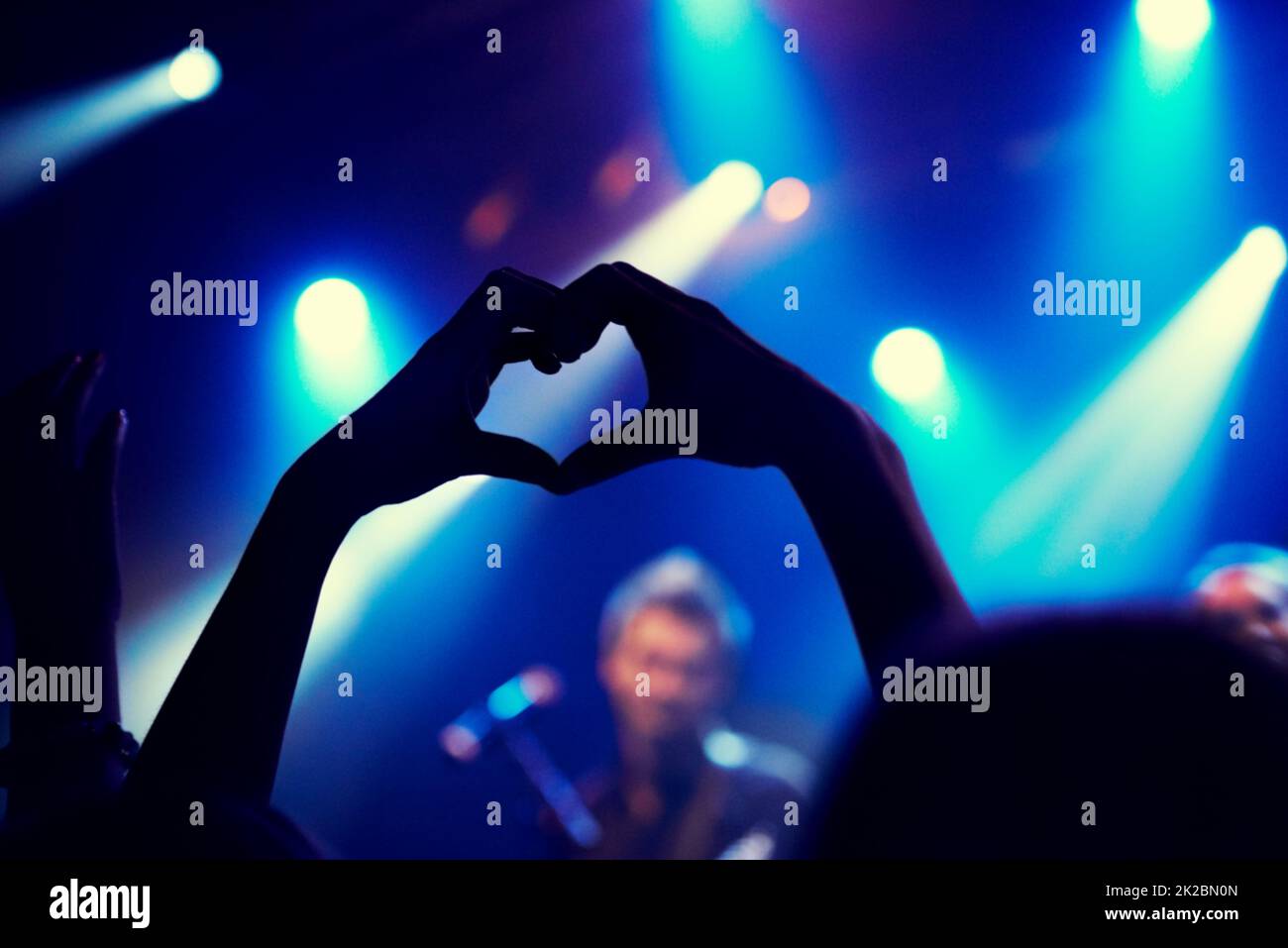 Eine junge Person, die der Band auf der Bühne Liebe und Licht zeigt. Dieses Konzert wurde ausschließlich für diesen Fototermin mit 300 Modellen und 3 Live-Bands geschaffen. Alle Leute in diesem Fotoshooting sind Model-veröffentlicht. Stockfoto