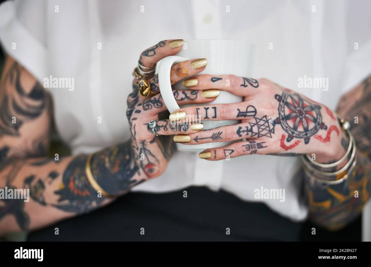 Sie liebt ihre Tattoos. Aufnahme einer nicht erkennbaren tätowierten Geschäftsfrau, die einen Becher in der Hand hält. Stockfoto