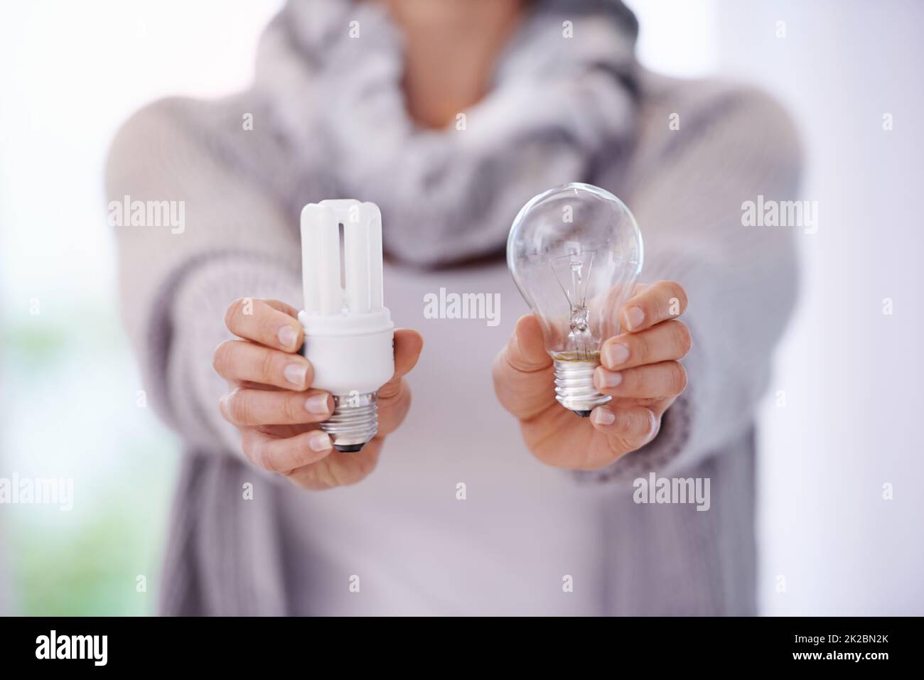 Halten Sie die Lichter länger brennen. Ein zugeschnittenes Bild einer Frau mit zwei verschiedenen Glühbirnen. Stockfoto