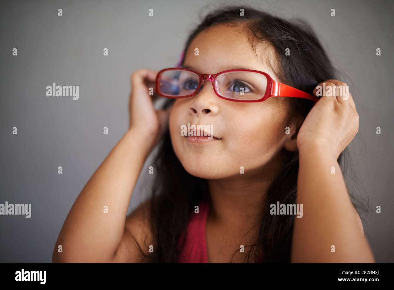 Ich glaube, sie passen zu mir, nicht Sie. Aufnahme eines niedlichen kleinen Mädchens, das eine Brille für Erwachsene anprobiert. Stockfoto