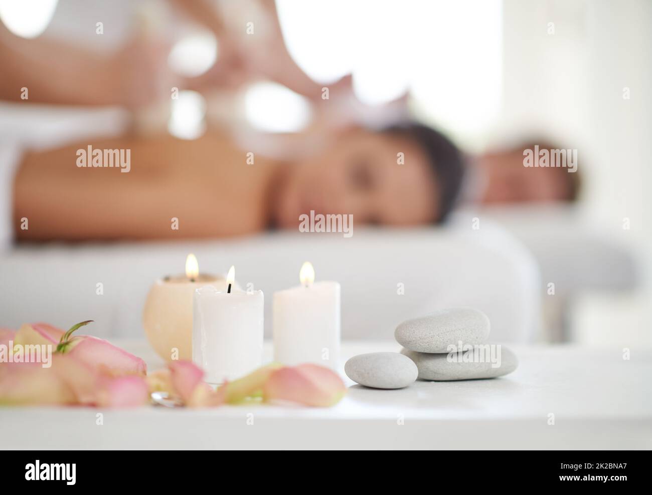 Wunderbare Entspannung. Ein Ehepaar erhält Massagen in einem Spa mit Kerzen im Vordergrund. Stockfoto