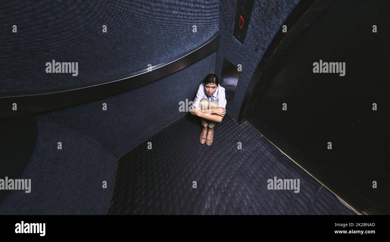 Nichts zu tun, als zu warten. Verzerrter Schuss einer jungen Frau, die in einem Aufzug gefangen ist. Stockfoto