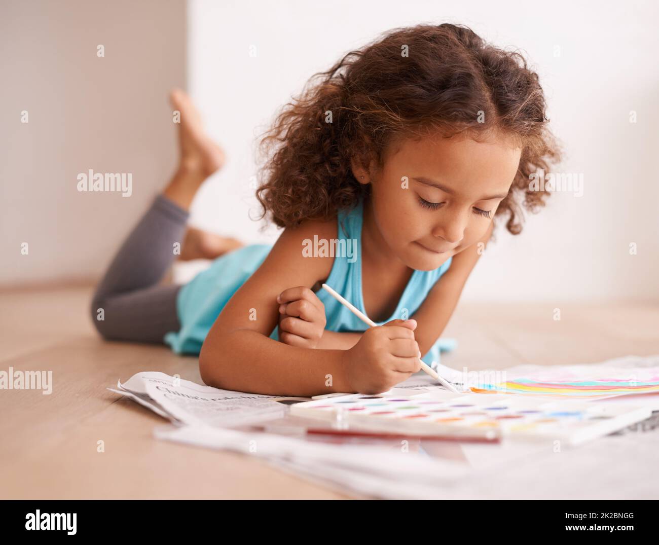 Ein Künstler im Bilden. Aufnahme eines kleinen Mädchens, das auf dem Boden liegt und ein Bild malt. Stockfoto