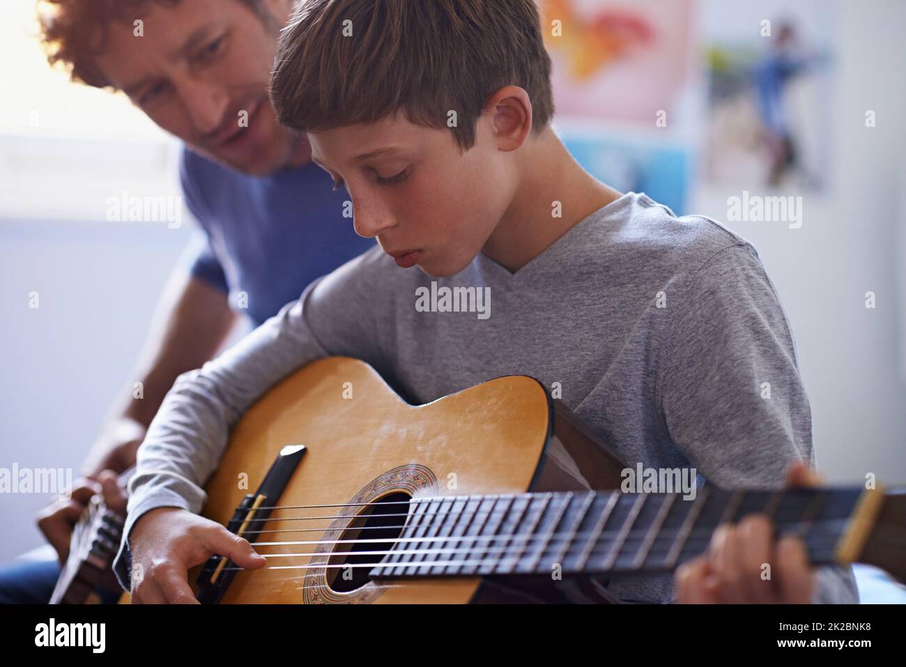 Das Studium der Saiten. Aufnahme eines Jungen, der von seinem Vater Gitarre spielen lernt. Stockfoto