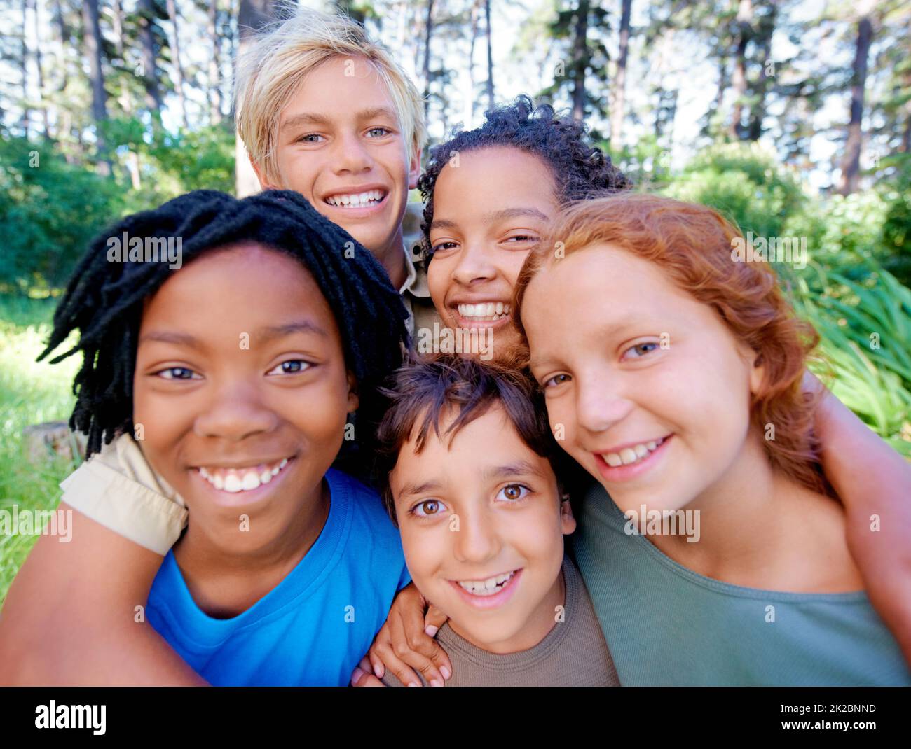 Spaß, Freunde und frische Luft. Eine Nahaufnahme des Bildes einer Gruppe von Kindern, die im Wald stehen und die Kamera anlächeln. Stockfoto